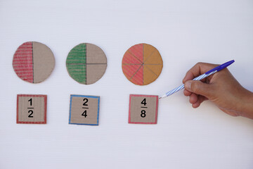 math teaching materials about fraction. hand hold pen. circle paper show parts of color separation. 