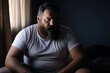 Portrait of a man with a beard sitting on the bed at home. Overweight and obesity concept. Obesity Concept with Copy Space.