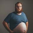 Fat man with red beard and glasses is holding his belly, on gray background. The concept of obesity. Obesity Concept with Copy Space.