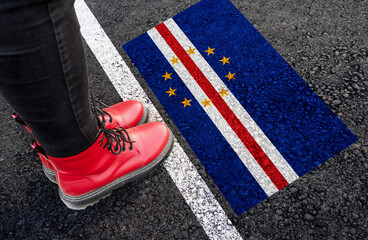 a woman with a boots standing on asphalt next to flag of Cape Verde and border
