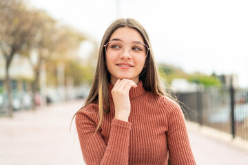 Wall Mural - Teenager girl at outdoors With glasses and thinking while looking up