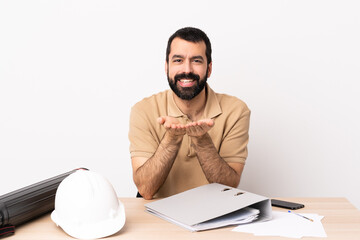 Wall Mural - Caucasian architect man with beard in a table holding copyspace imaginary on the palm to insert an ad.