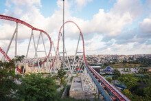 Roller Coaster In An Amusement Park Located On A Hill On A Sunny Cloudy Day