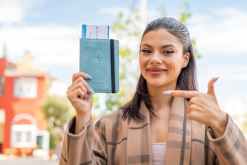 Canvas Print - Young pretty woman holding a passport at outdoors and pointing it