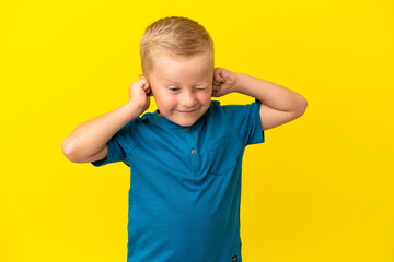 Wall Mural - Little Russian boy isolated on yellow background frustrated and covering ears