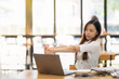 © Wasana - A female employee stretching lazy at the desk to relax while working in the office. Feeling stressed and achy from work.