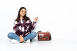 © luismolinero - Young student woman sitting on the floor pointing finger to the side