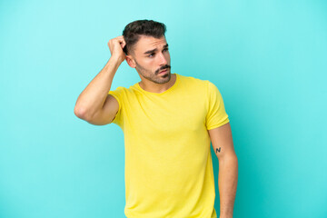 Young caucasian man isolated on blue background having doubts while scratching head
