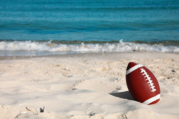 Wall Mural - American football ball on beach. Space for text