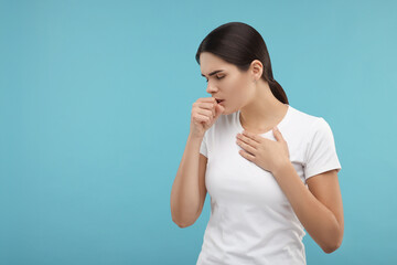 Poster - Woman coughing on light blue background, space for text. Cold symptoms