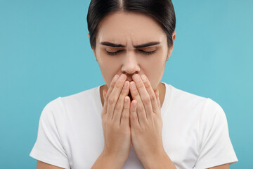 Poster - Woman coughing on light blue background. Cold symptoms