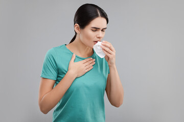 Poster - Woman with tissue coughing on grey background, space for text. Cold symptoms