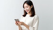 © Santy Hong - Pretty young asian woman using smartphone standing on isolated white background. Excited Beautiful young asian shopping online payment with mobile phone. Playing game on smartphone.