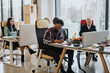 © qunica.com - A multicultural office scene with focused employees working at desks. Men and women of various ages demonstrate teamwork and professionalism in a contemporary workspace.