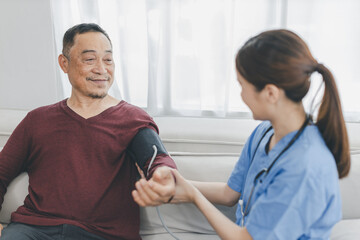 Caregiver nurse measuring blood pressure by using digital sphygmomanometer Senior patient at home. Caregiver nurse using medical device to measure blood pressure Senior patient