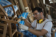 © amorn - Carpenter working at woodwork workshop. Joiner in furniture workshop. Worker using carpenter tools making furniture. Start up and small business concept