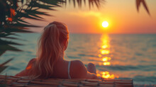 Woman Relaxing On The Beach And Watching Sunset And The Sea