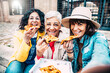 Happy friends enjoying street food in the city center - Three senior women eating pizza slice sitting outside - Life style concept with Italian food culture and european holidays concept
