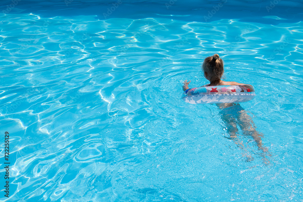 Child girl learn to swim with an inflatable ring in the pool