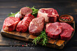 Assortment of fresh meat on wooden board: various types of beef steaks