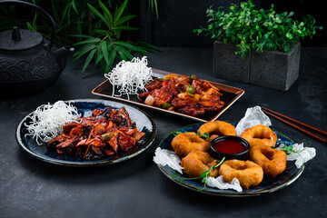 Wall Mural - Asian dinner set of chicken fillet with shiitake mushrooms, onion, celery, sweet pepper and crispy squid rings in dough with sauce and microgreens.