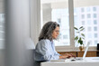 © insta_photos - Busy mature senior business woman working in office using laptop. Middle aged old professional lady executive manager looking at computer digital technology sitting at desk. Authentic candid shot.