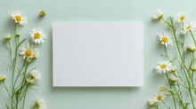 White Blank Card Mockup With Daisies Flowers In Decoration Against A Green Background. Spring Greeting Card Mockup Template And Invitation Card Mock Up