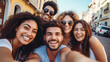 Multiethnic group of friends taking selfie with smartphone while traveling together