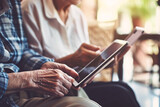 a close-up of an old woman and a man holding a tablet