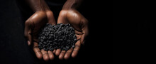 Slavery In Mining. African Hands Holding Coltan Grains Over Dark Background With Copy Space