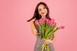 © Prostock-studio - Gleeful young woman with lustrous hair, holding a lush bouquet of pink tulips