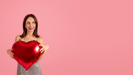 Wall Mural - A woman with a captivating smile holds a red heart-shaped balloon