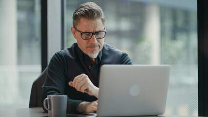 Wall Mural - Businessman using laptop computer in office. Happy middle aged man, entrepreneur, small business owner working online, thinking.