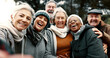 © Clement C/peopleimages.com - Happy, selfie and senior friends in a park while walking outdoor for fresh air together. Diversity, smile and group of elderly people in retirement taking picture and bonding in a forest in winter.