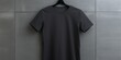 A black t-shirt is hanging on a metal wall. This image can be used for fashion, clothing, or retail-related projects