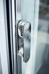 Poster - A detailed close-up of a door handle on a glass door. This image can be used to showcase modern architecture or to symbolize entrance and access