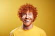 © Ari - Smiling red-haired man with curly hair wearing a yellow shirt against a vibrant yellow studio background