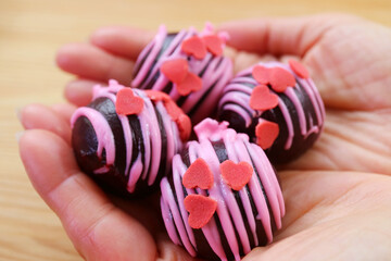 Wall Mural - Delectable Chocolate Cake Pops Coated with Heart Shaped Strawberry Royal Icing in Hand