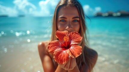 Poster -  a woman standing on a beach holding a flower in front of her face and a body of water in the background.