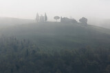 Fototapeta Uliczki - Beautiful scenery of Chapel Vitaleta on a hilltop in idyllic Tuscan countryside with rolling hills veiled in morning fog in an ethereal mysterious atmosphere, in Pienza, Val d'Orcia, Tuscany, Italy
