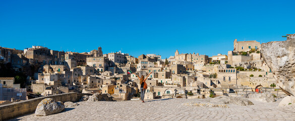 Wall Mural - Woman tourist enjoying view of ancient town of Matera (Sassi di Matera) in Italy