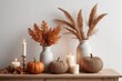 Cozy autumn home interior various decorative wicker pumpkins, candles, seasonal flowers in vase on the wooden console with white wall background