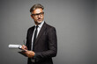 © ViDi Studio - Side view adult employee business man corporate lawyer wear formal black suit shirt tie work in office hold clipboard with paper account documents look aside on area isolated on plain grey background