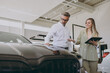 © ViDi Studio - Adult man customer male buyer client wear shirt consult with salesman signs documents choose auto wants to buy new automobile in car showroom vehicle salon dealership store motor show. Sales concept.