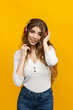 © makedonski2015 - A captivating woman finds delight in listening to music with her headphones on in a bright yellow environment