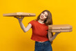 © makedonski2015 - A female pizza delivery worker is captured standing against a backdrop of yellow, holding a bunch of pizza boxes, dressed in a bright red T-shirt