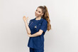 © makedonski2015 - Portrait of an attractive nurse in a blue suit on a white background. The woman points her hand to the side. Mockup