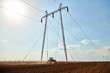 © Westend61 - Tractor cultivating field near electricity pylon on sunny day