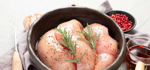 Wall Mural - Raw marinated chicken meat with rosemary and sauce in a grey bowl. Marinating meat for cooking.