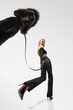 © Lustre Art Group  - Wide angle. Woman in fashion outfit walking her purebred black poodle on leash against white studio background. Concept of fashion and style with pets, companionship, pet lovers, motion.